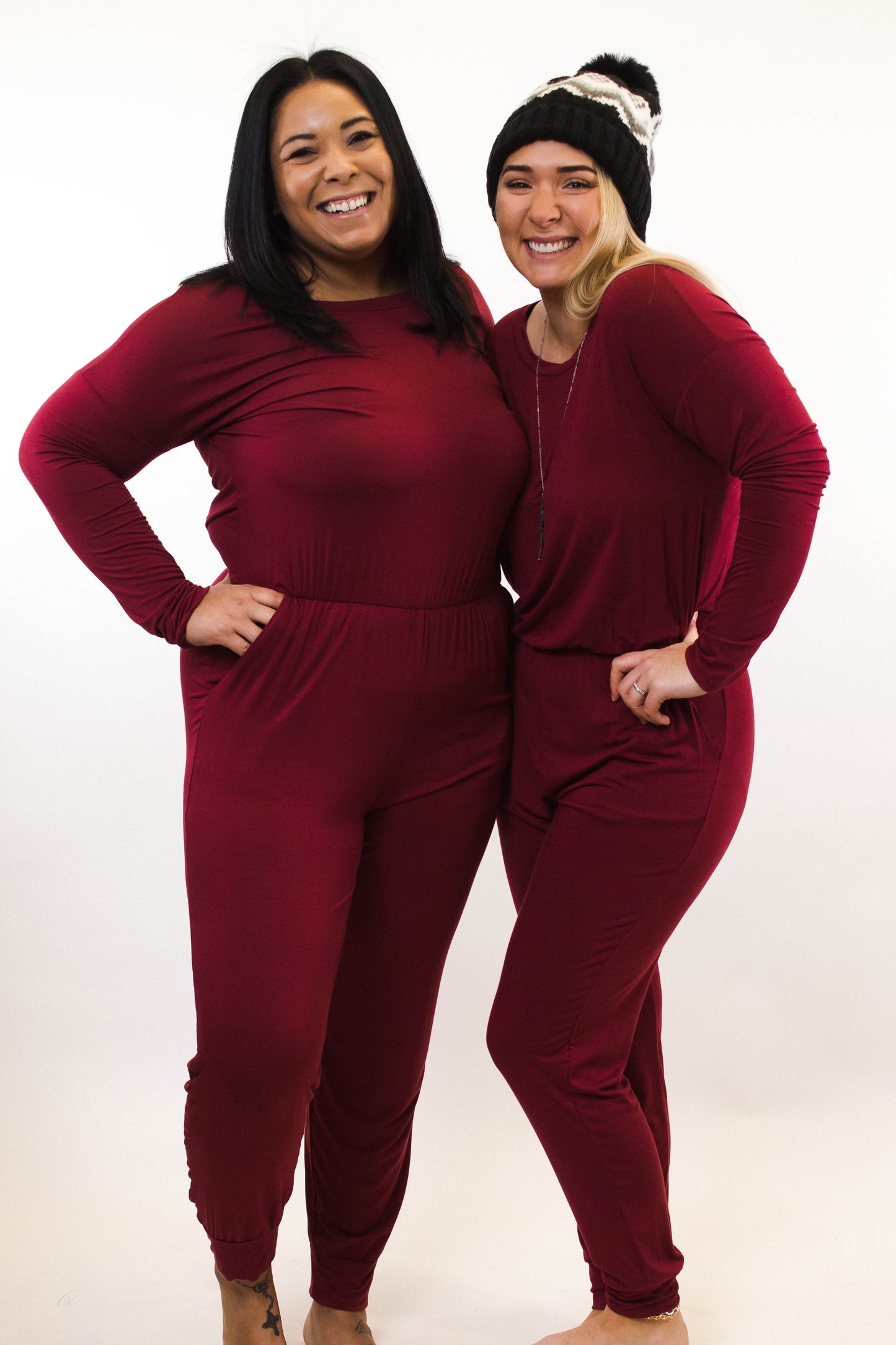 two ladies wearing matching red jumpsuits smiling hands on hips
