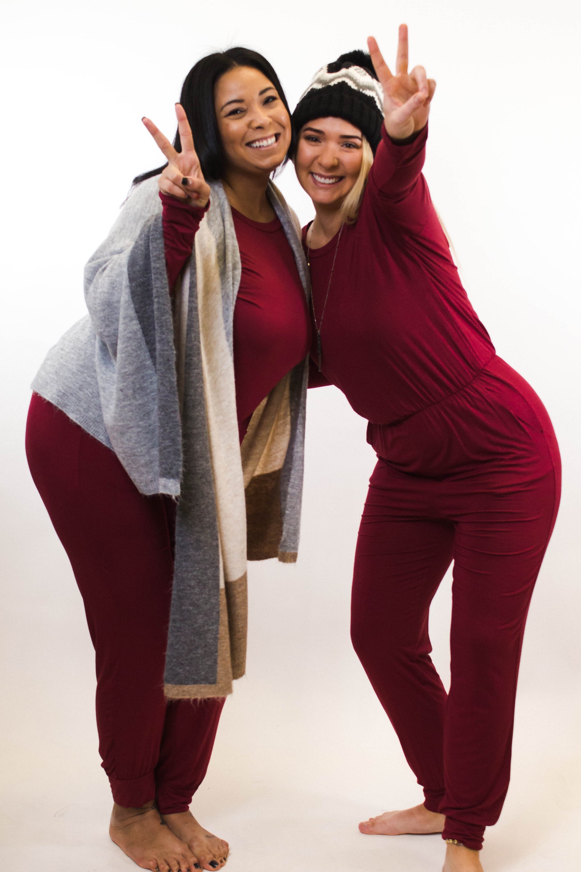 friends wearing matching red jumpsuits winter hat grey cardigan peace signs smiling